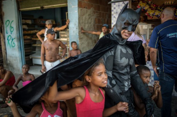 Children-play-around-a-man-disguised-as-Batman-at-the-Favela-do-Metro-slum-near-to-the-Maracana-stadium-in-Rio-de-Janeiro